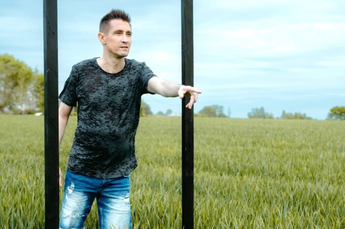 Baptiste Valloy sortant d'une porte dans un champ le doigt pointant vers l'avant